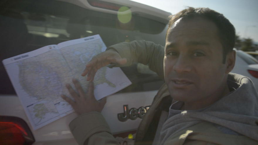 Alom leans on the car to explain our route across the US.